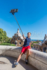 A young 11-12 year old boy takes a selfie, from an overlook of Gaudí's architecture, at Park Güell in Barcelona, Spain.
