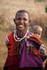 A Masai woman in traditional clothing and jewelry carries her baby on her back in a small Masai village in northern Tanzania. To purchase this image, please go to my stock agency click here.