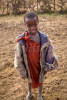 A young Masai boy wearing a tattered western style coat stands by the roadside in northern Tanzania. To purchase this image, please go to my stock agency click here.