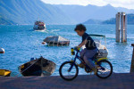 A young Italian boy rides his bicycle past the harbor overlooking beautiful Lake Como in the village of Varenna. To purchase this image, please go to my stock agency click here.