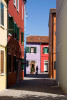 Silhouette of a woman passer by against the colorful buildings of Burano Island, Italy. To purchase this image, please go to my stock agency click here.