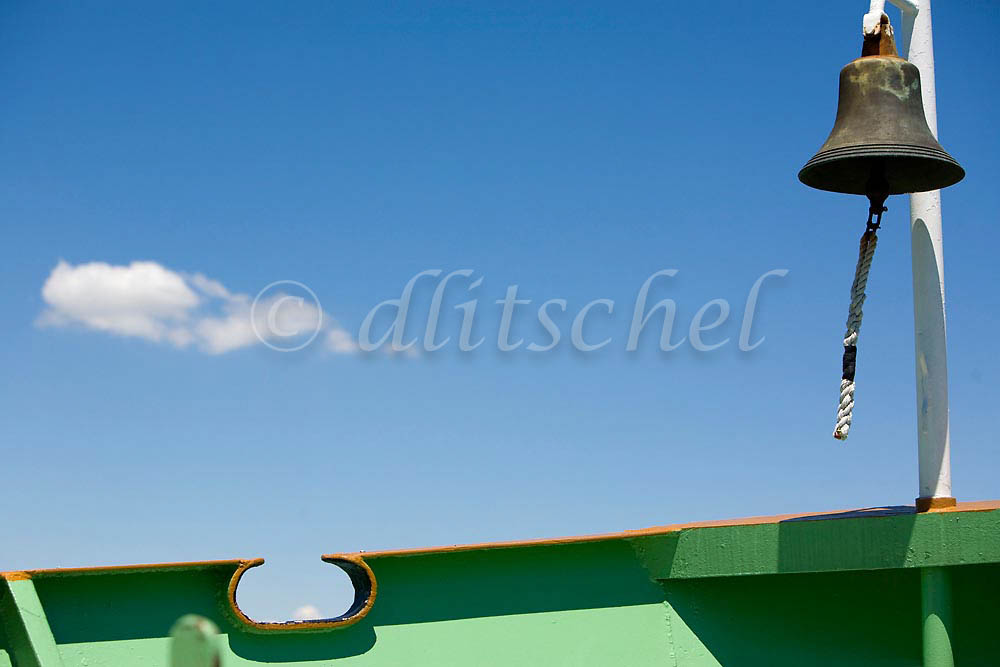 A view of a boat bow, bell and cloud in a clear blue sky on the Vaporetto (water taxi) from Venice to Burano Island, Italy. To purchase this image, please go to my stock agency click here.