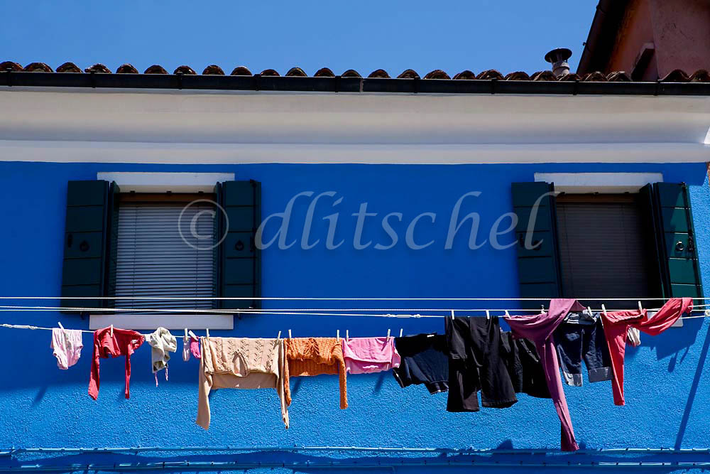 Laundry dries on a second story clothes line against a deep blue wall of a house in Burano Island, Italy. To purchase this image, please go to my stock agency click here.