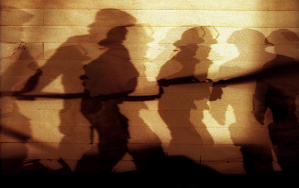 Volunteer firefighters' shadows merge while working closely together to put out a four-alarm barn fire in Douglas Township, Pennsylvania. Fifteen fire companies from the area were called to the scene which destroyed the building.