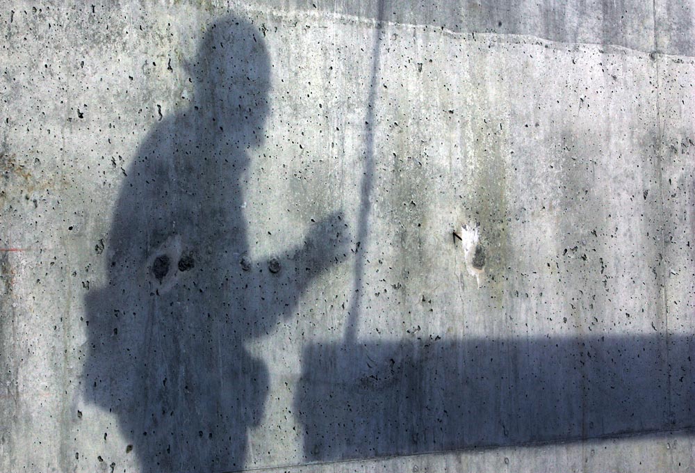 An ironworkers' shadow is cast against the building’s cement core as he guides a beam. 