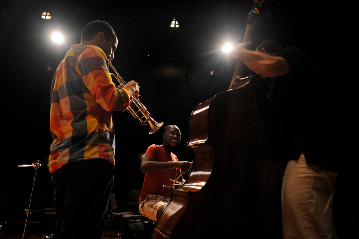 Hatian drummer JonBern Thomas, center, plays alongside trumpist Amir ElSaffar, of New York City, left, and bassist Gregg August, right, as fellows with OneBeat rehearse on Wednesday, September 19, 2012 at the Atlantic Center for the Arts in New Smyrna Beach, Fla. OneBeat is an intentional cultural exchange program that brings together over 30 young musicians from around the world to live together and write and perform music. The program is an initiative of U.S. State Department's Bureau of Educational and Cultural Affairs. (David Manning for The New York Times)