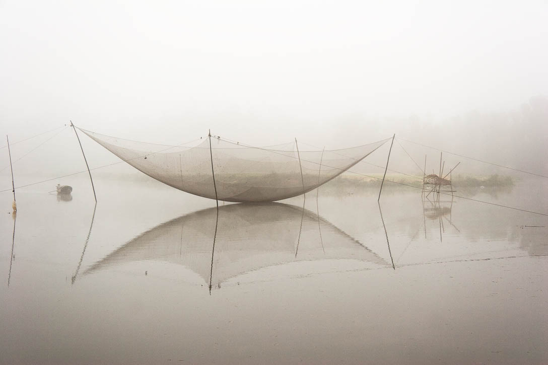 Fishing net on a river between My Son and Hoi An, Vietnam, In the early morning mist with a fishing boat approaching from the left. This photo just won an honorable mention in the International Photo Awards (IPA) 2010 competition. Photo by Jay Graham
