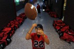 Rangeview High School ball boy and son of head coach Dave Gonzales, Max Gonzales, 10, plays with a football in the hallway as the players bags can be seen lining the walls before the team played Gateway High School  Friday 09/11/09 at Aurora Public School Stadium.  Photo by Matt McClain
