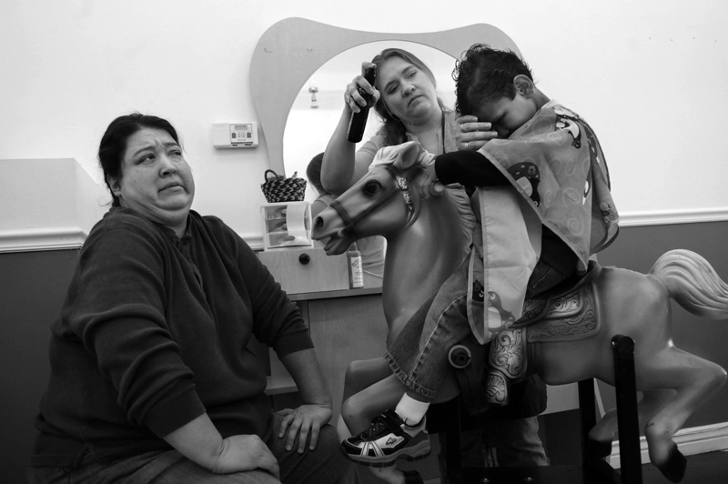 Lelana Fayre watches as her son, Pandu Fayre has his first haircut with his new parents at Lollilocks Kids Salon by Tobie Booth Friday 05/01/09 the day before the celebration of his sixth birthday.  Photo by Matt McClain 