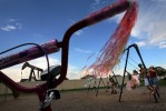 Gabrielle Van Winkle, 8, plays on a swing as an oil derrick is seen in the background of park equipment in the Summit View neighborhood of Fredrick Colo.  Photo by Matt McClain