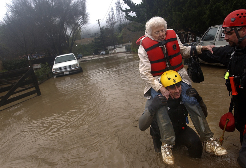 Winetta Davis is carried with the help of David Haas, center and Ed Morlan, right, both of Ventura County Sheriff Search and Rescue as people are evacuated from their homes in Casitas Springs, Calif.  Photo by Matt McClain