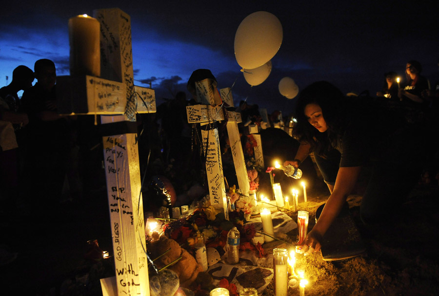 Rachel Fogleman, 13, of Aurora, CO lights candles near a makeshift memorial that includes twelve crosses across the street from the Century Aurora 16 movie theater on Sunday July 22, 2012 in Aurora, CO.  The crosses represent the twelve people who were killed in a deadly shooting Friday morning at the movie theater.  