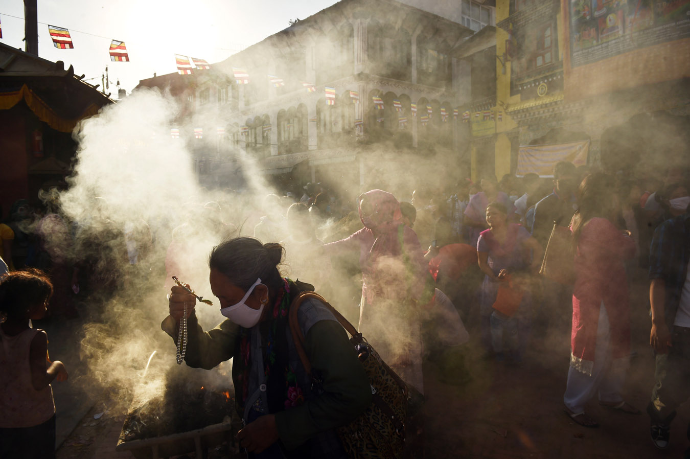 Smoke engulfs people as they celebrate Buddha Purnima which commemorates the birthday of Buddha near the Boudhanath stupa on Monday May 04, 2015 in Kathmandu, Nepal. Scores of people gathered for the festival near the historic stupa. (Photo by Matt McClain/ The Washington Post)