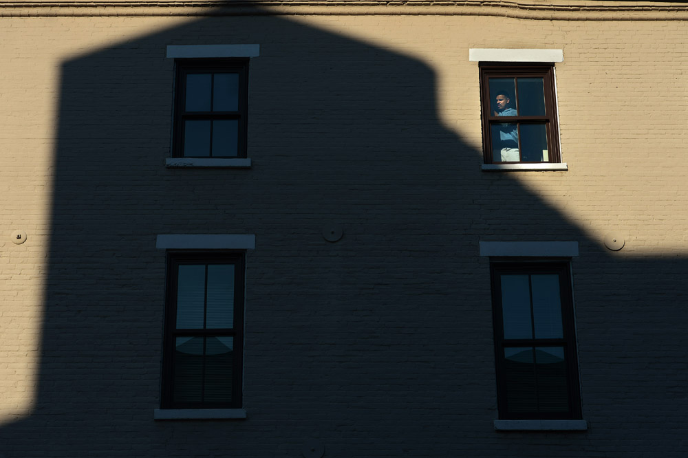 A shadow of a building is cast on another building as a man works on a window on Thursday February 21, 2013 in Alexandria, VA.  (Photo by Matt McClain for The Washington Post)