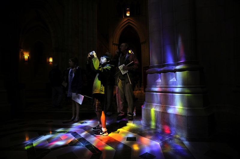 After attending The Sunday of the Passion: Palm Sunday service, Philip Cloeter, 10, is bathed in the light from a stained glass window as he takes a photo as his sister, Adrienne Cloeter, 11, and father, Phil Cloeter, right, are seen holding palms at Washington National Cathedral on Sunday April 17, 2011 in Washington, DC.  Palm Sunday begins Holy Week which concludes on Easter Sunday.  The family was on vacation from Sacramento, CA.  (Photo by Matt McClain/For The Washington Post)