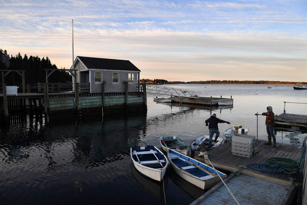 Lobsterman, Bruce Fernald, center, climbs into a row boat on Little Cranberry Island as Kevin Wilson, right, looks on Friday April 29, 2016 in Islesford, ME. The pair were taking the small boat to Fernald's lobster boat to prepare for a day of catching lobsters. Wilson works on Bruce's boat. Fernald comes from a long line of lobstermen. China has become a large market for Maine lobster. (Photo by Matt McClain/ The Washington Post)