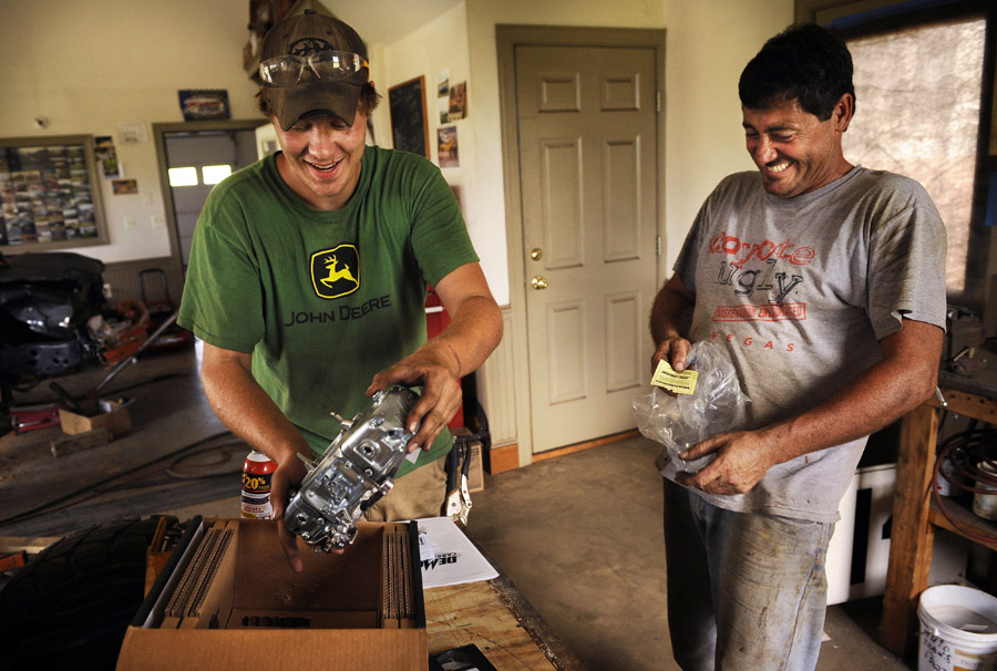Zach Orndorff, 18, left, and his father, Bill Orndorff react to unwrapping a carburetor they received by delivery on Thursday August 23, 2012 in Woodstock, VA.  The carburetor was used in Bill's demolition derby car.  