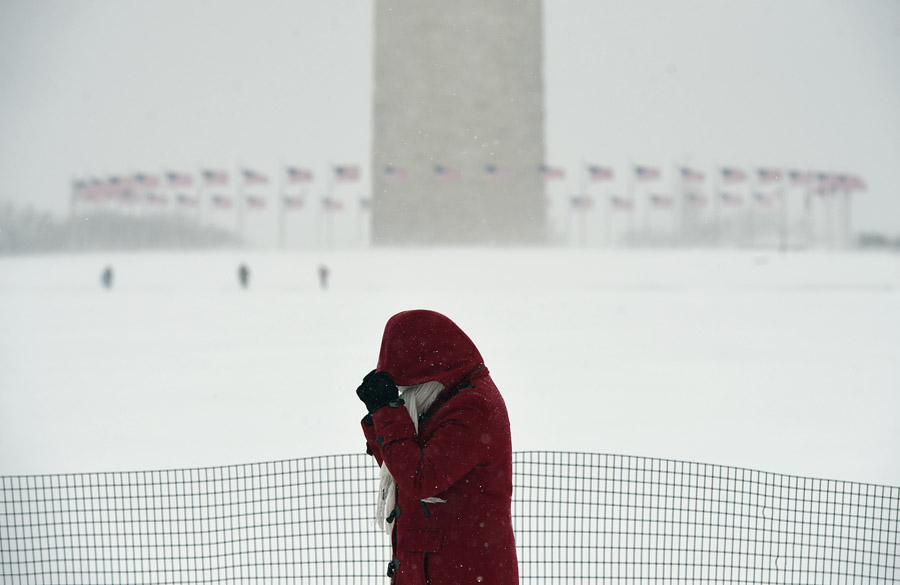 A woman walks near the Washington Monument on Saturday January 23, 2016 in Washington, DC. A large snow event was being predicted for Washington, DC area. (Photo by Matt McClain/ The Washington Post)