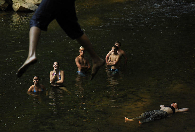 Stuart Sherbs, top, uses a rope swing to lauch himself towards the water to join Mica D'Alesandro, center left to right, Jessica Huskey, Connor Eash, Chris Winter, Sean Winter, and Bekah Hogg as people cool off from the summer heat in the Patapsco River in Carroll County, MD on Monday July 16, 2012.  (Photo by Matt McClain for The Washington Post)