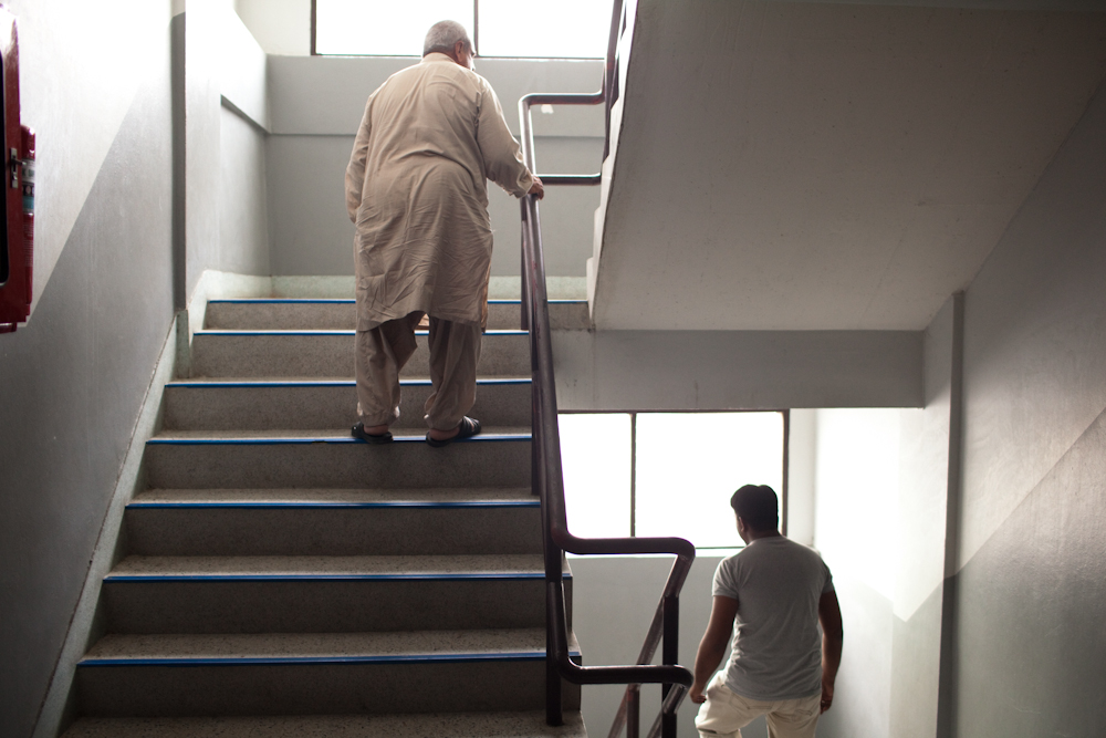 Two men walk the stairwell in one of the main buildings that house hundreds of asylum-seekers, mostly from Pakistan, Somalia and Sri Lanka. Mar. 2015