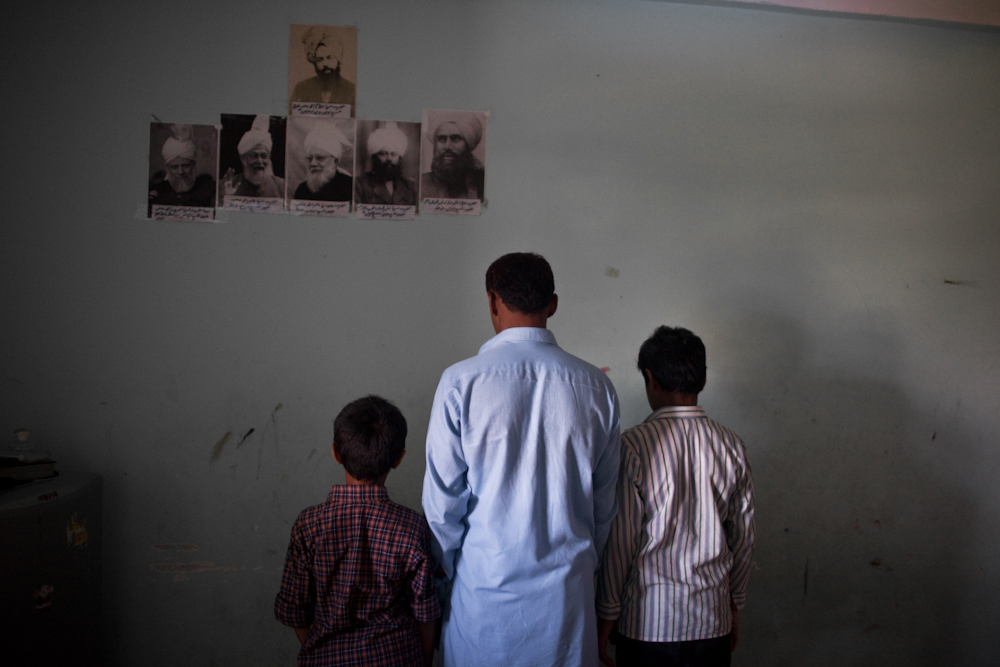 A father and his two sons from Islamabad, Pakistan, seeking asylum, practice their faith inside their room. They are Ahmadi Muslims, a religious minority, who is often targeted and discriminated against by other Muslims in Pakistan. Apr. 2015
