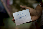 Sakeena, an asylum-seeker from Lahore, Pakistan, holds a note with information about her son who is being held at the Immigration Detention Center in Bangkok. Asad, 22,  was arrested for having an expired visa outside of a nearby seven eleven store on the outskirts of Bangkok. He has been detained for 5 months inside the Immigration Detention Center. Sakeena and her husband wait patiently inside their room hoping to receive any news regarding their son. Mar. 2015