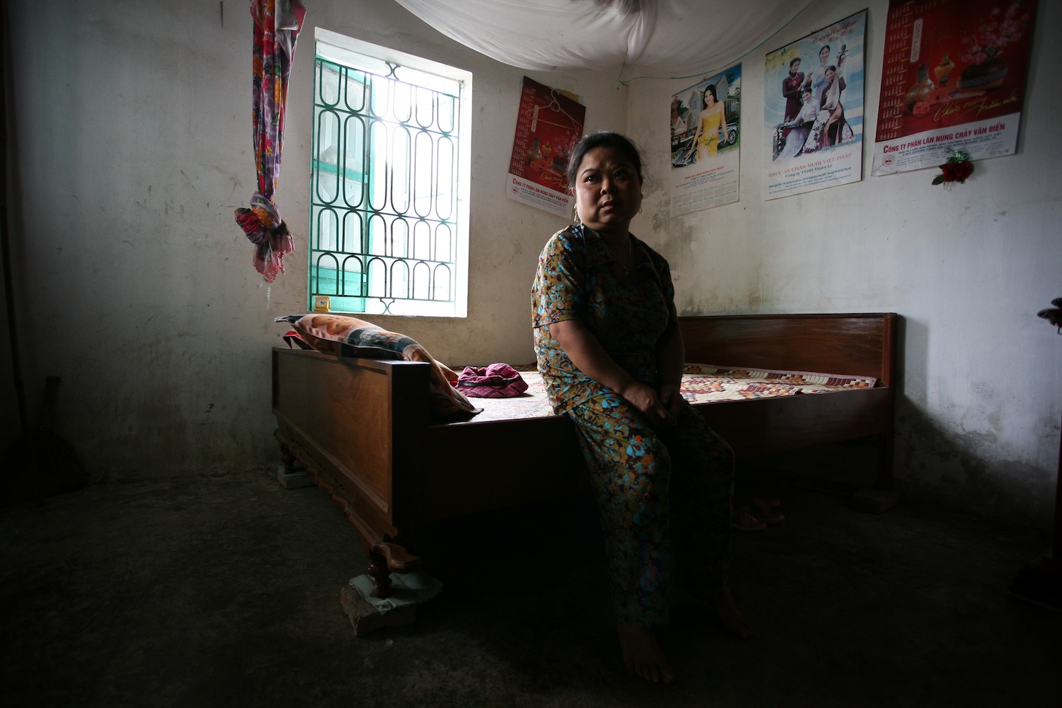 Standing about a metre tall, Mai Thi, 28, Agent Orange victim, patiently waits for her mothers return to comfort her in the bedroom of their home in the Kim Dong district of Nhat Tan, Vietnam.