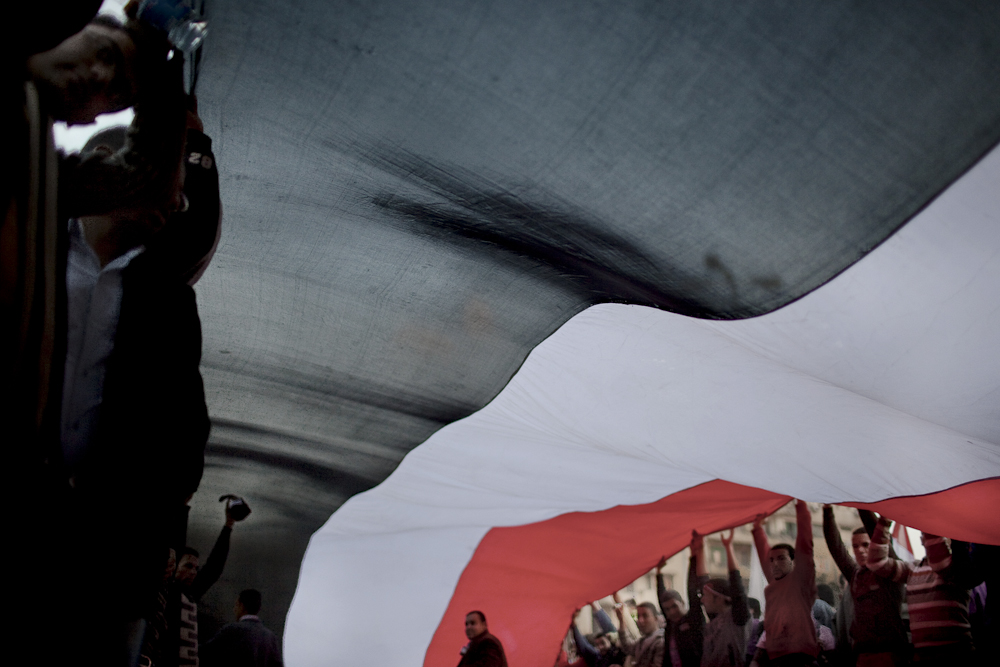 Proud Egyptians carry a giant national flag through Tahrir Square in Cairo.Tuesday, February 8, 2011.