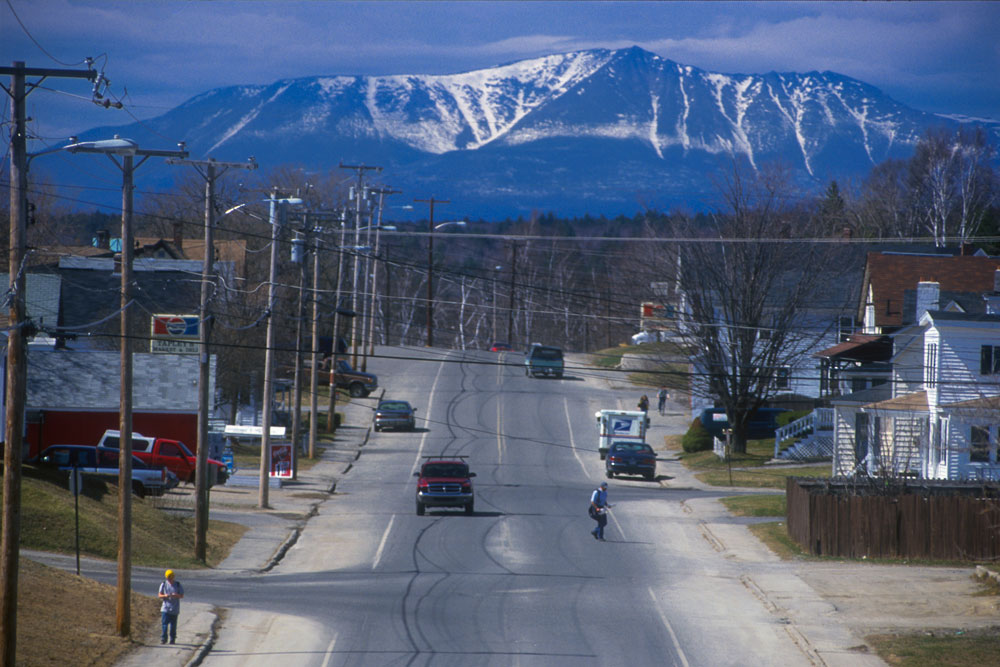 Mount Katahdin looms in the distance as a truck carries logs to a