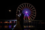 The bride & groom kiss in front of the Great Seattle Wheel on the Seattle waterfront during their wedding at the Seattle Aquarium. (Wedding Photography by Scott Eklund - Red Box Pictures)