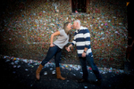 The Jennifer & Lincoln make a stop at the gum wall during their Seattle Pike Place Market engagement session. (Photography by Scott Eklund /Red Box Pictures)