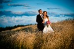 Pauline and Scott watch the sun set while standing in the tall grass at the Golf Club at Newcastle near Seattle, Wash. (Wedding Photography by Scott Eklund/Red Box Pictures)