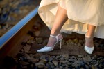 Michelle shows off her fancy white shoes as the bride walks along the railroad tracks in Sumner, Washington after her wedding at The Attic. (Photography by Scott Eklund/Red Box Pictures)