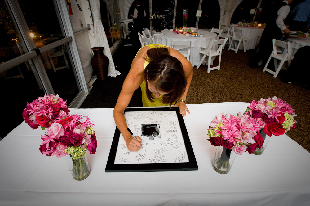A wedding guest signs the mat board around a photograph of Scott and Pauline at their reception at the Golf Club at Newcastle near Seattle. Photography by Scott Eklund/Red Box Pictures)