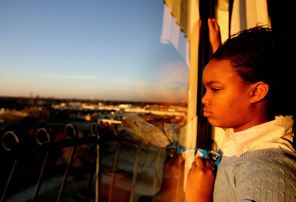 Brittany Powell, 13, looks out her hotel window in late December 2005 at the Windsor Suites Hotel in Houston. She and her family were Katrina evacuees who had been living in hotels for 4 months. She and her 5 siblings and cousins had been out of school since the hurricane.