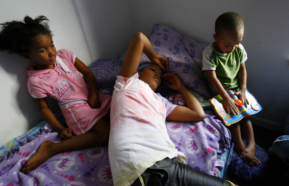 From left, Brishawn Powell, 7, her sister Brittany Powell, 13, and their cousin Myron Powell, 2, rest in their New Orleans seventh ward duplex.