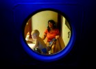 Seen through a porthole, Margaret Shiver watches television and babysits her grandson Kaleb Shiver, 2, in the tug boat 