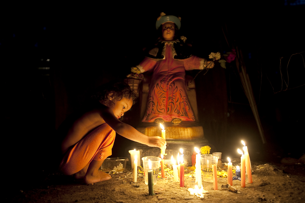 A child lights candles at an altar to Niño de Atocha, the patron saint of those unjustly imprisoned, a protector of travelers, and rescuer of those in peril during the annual celebration of Venezuela’s María Lionza religious cult at Sorte Mountain in the state of Yaracuy, Venezuela.