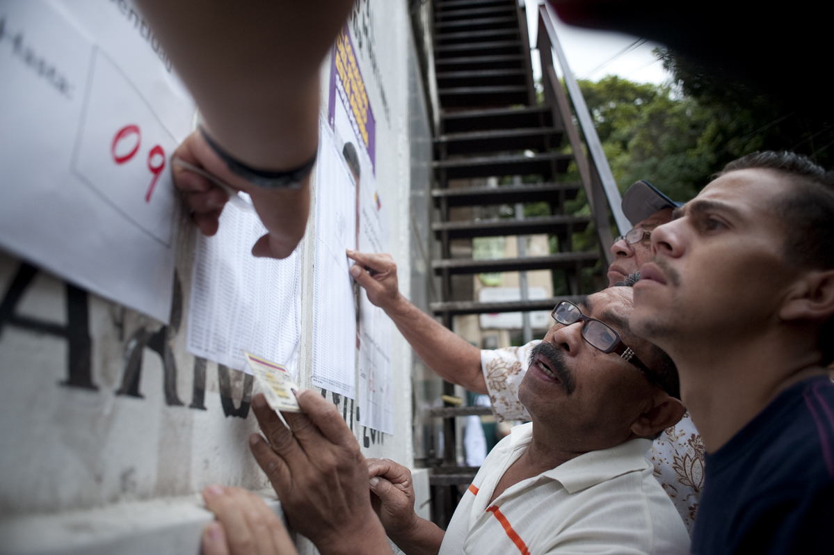 People look for their names at a polling station before voting begins in Petare, a slum in Caracas.