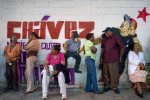 People line up to vote early Sunday morning in Petare, a  Caracas slum, in front of a new mural depicting President Hugo Chavez as a rapper. Recently, artists around the city have been creating youthful images of Chavez in an effort to distract from his recent battle with cancer.
