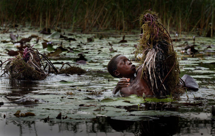 Boys dive in a swamp for roots to be cleaned and boiled to eat. The corn crop in the village had failed because of drought and local residents began scavenging for whatever they could find.