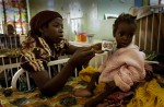 A mother tries to give her daughter formula while recovering at a feeding center in Malawi.