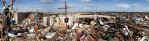 A makeshift cross rises over the remnants of a home.