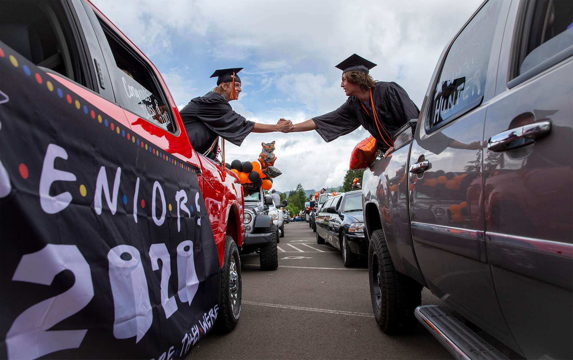 Mohawk High School seniors Dalton Martin and Hunter Carter shakes hands from the backs of their trucks as they stage in the parking lot to receive their diplomas as graduates of the Class of 2020. The traditional graduation at the school was cancelled due to Covid-19 so seniors had a drive-through celebration that went through Marcola. [Andy Nelson/The Register-Guard] - registerguard.com