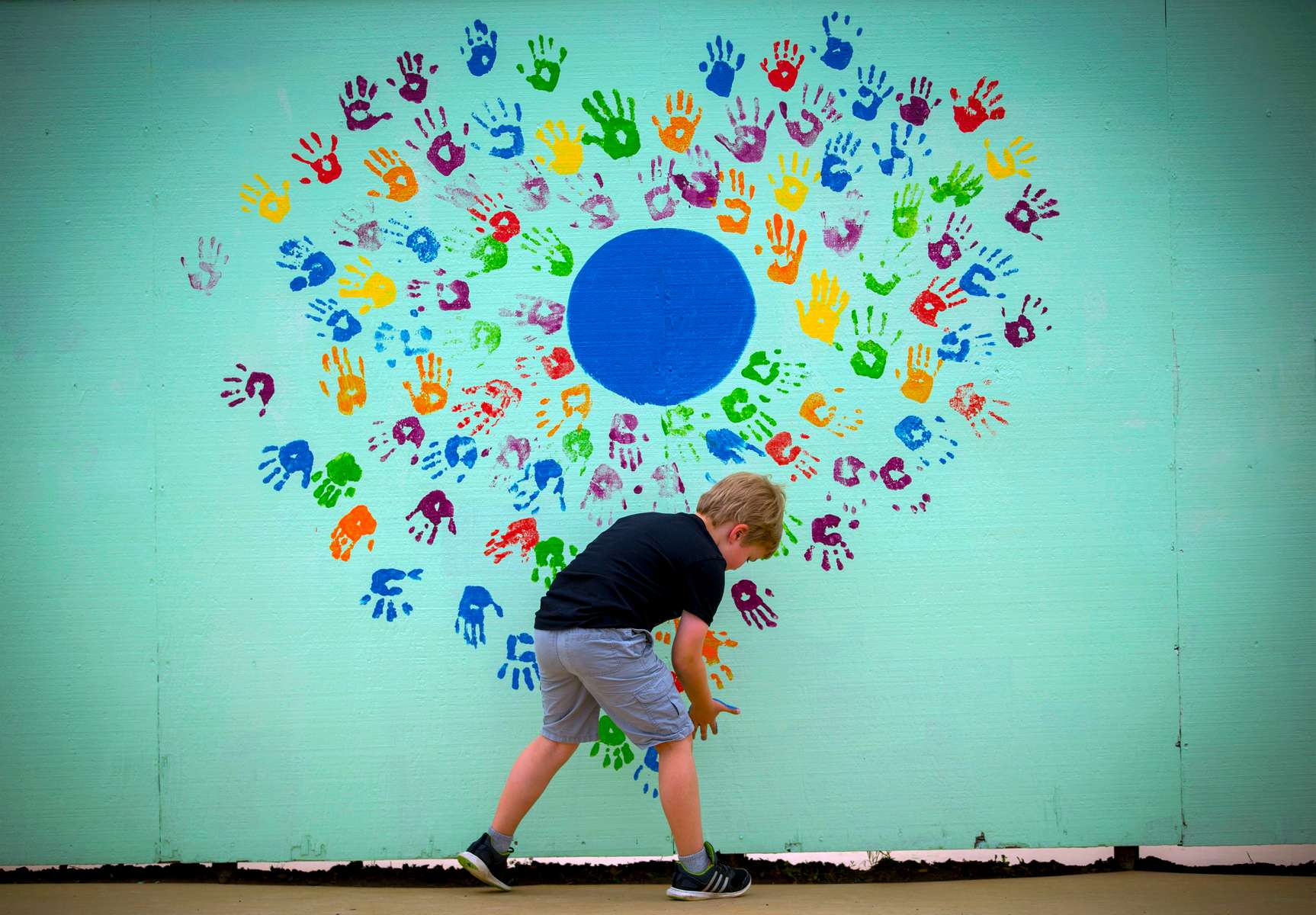 Second grader Harper Stiles puts his handprint on a mural with fellow students' prints during Earth Day activities at Adams Elementary School in Eugene, Ore., Friday, April 20, 2018. The activities were part of a partnership with the school and the University of Oregon's Environmental Leadership Program. There were nine different stations at which the students participated in activities like understanding recycling practices, a solar oven, tent-building relay races, planting and weeding in the school's garden, and planting 13 trees near the school. Earth Day began in 1970 and is officially on April 22.  (Andy Nelson/The Register-Guard via AP)