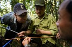 Kevin Anchukaitis, postdoctoral research fellow at the Lamont-Doherty Earth Observatory's Tree Ring Laboratory, left, listens with mobil ranger team leader Cao Minh Tri, as Le Canh Nam, right, discusses a core sample from a fokienia tree.  The Vietnamese rangers and researchers are essential to the success of work done by the tree ring scientists providing logistical support and intimate knowledge of the forest and its environs.
