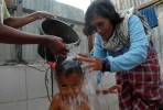 Juriah washes Reza in the makeshift washing area they have behind their home in the Lampuloneighborhood in Banda Aceh, Indonesia.