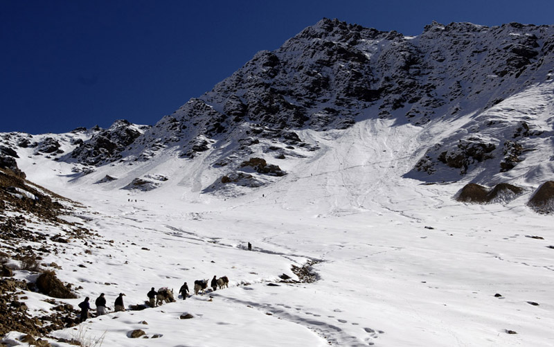 Mule and men ascend the steep and snowy slopes from Khenj, Afghanistan to the emerald mines where miners work year round. Geologists believe emeralds are found in Afghanistan only in the Panjshir Valley. 