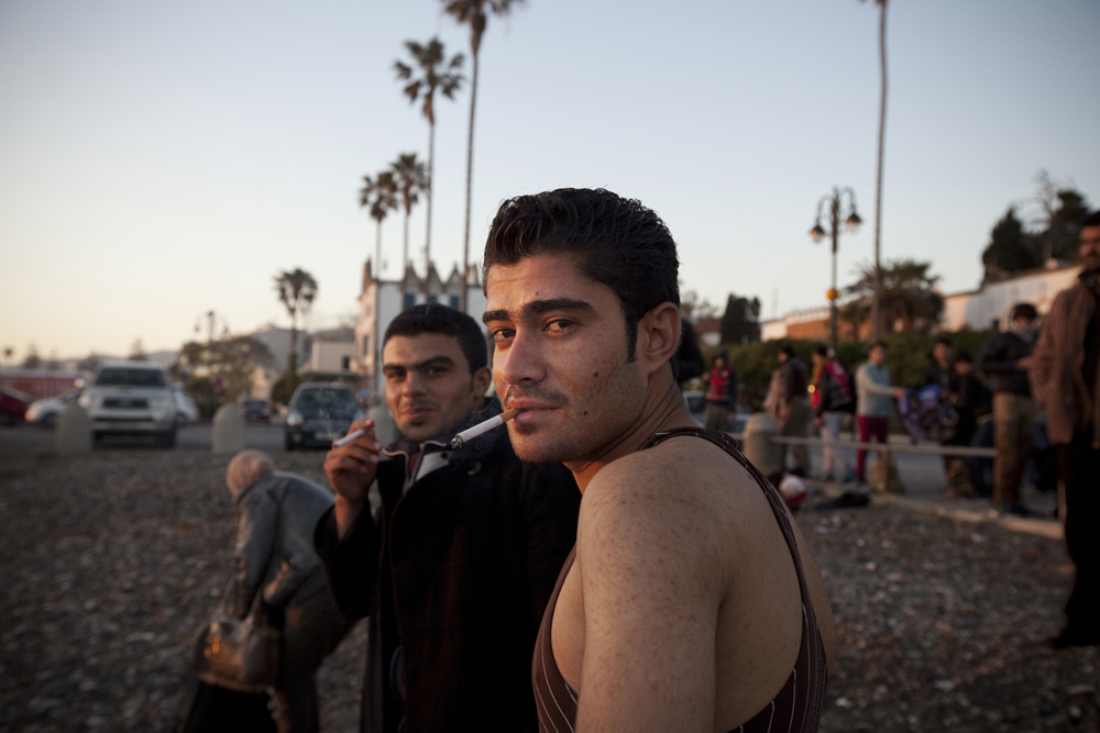 Greece, Kos island 2015Arrival. Two young Syrian men ejoying a cigarette finally, after their arrival from Turkey to Greece.   Immigrants are mostly transferred via the use of small boats from the Aegean coast and, in the cases of the Marmara Sea and the Turkish Mediterranean coasts, by old vessels carrying up to 1,000 people. In any case a smooth flow of around 250 people on a daily basis is ensured. Depending on weather conditions, the authories’ counteractions and the iron law of supply and demand, numbers fluctuate from less than 30 to over 600 migrants per day.