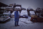 Akira Sugawara, 56, walks through a massive car pile where he works as a security guard. Vehicles destroyed or left behind in the chaos of last years tsunami are piled high, waiting for their owners to come and claim them in Ishinomaki, Japan.